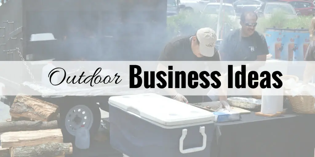 two men working on food preparation outside with smoker in background smoking food.